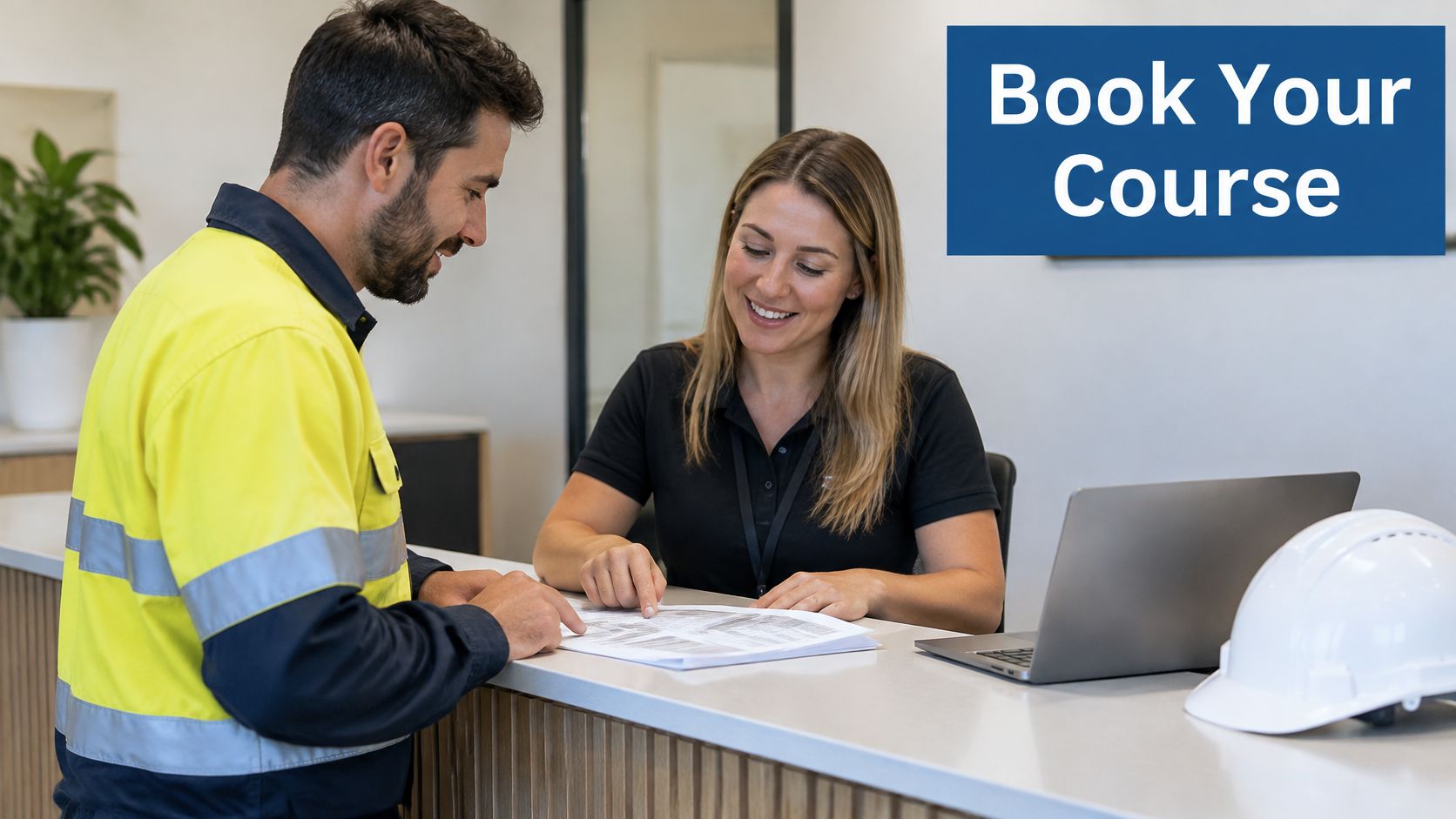 A construction worker in high-visibility gear speaks with a receptionist while booking a training course.